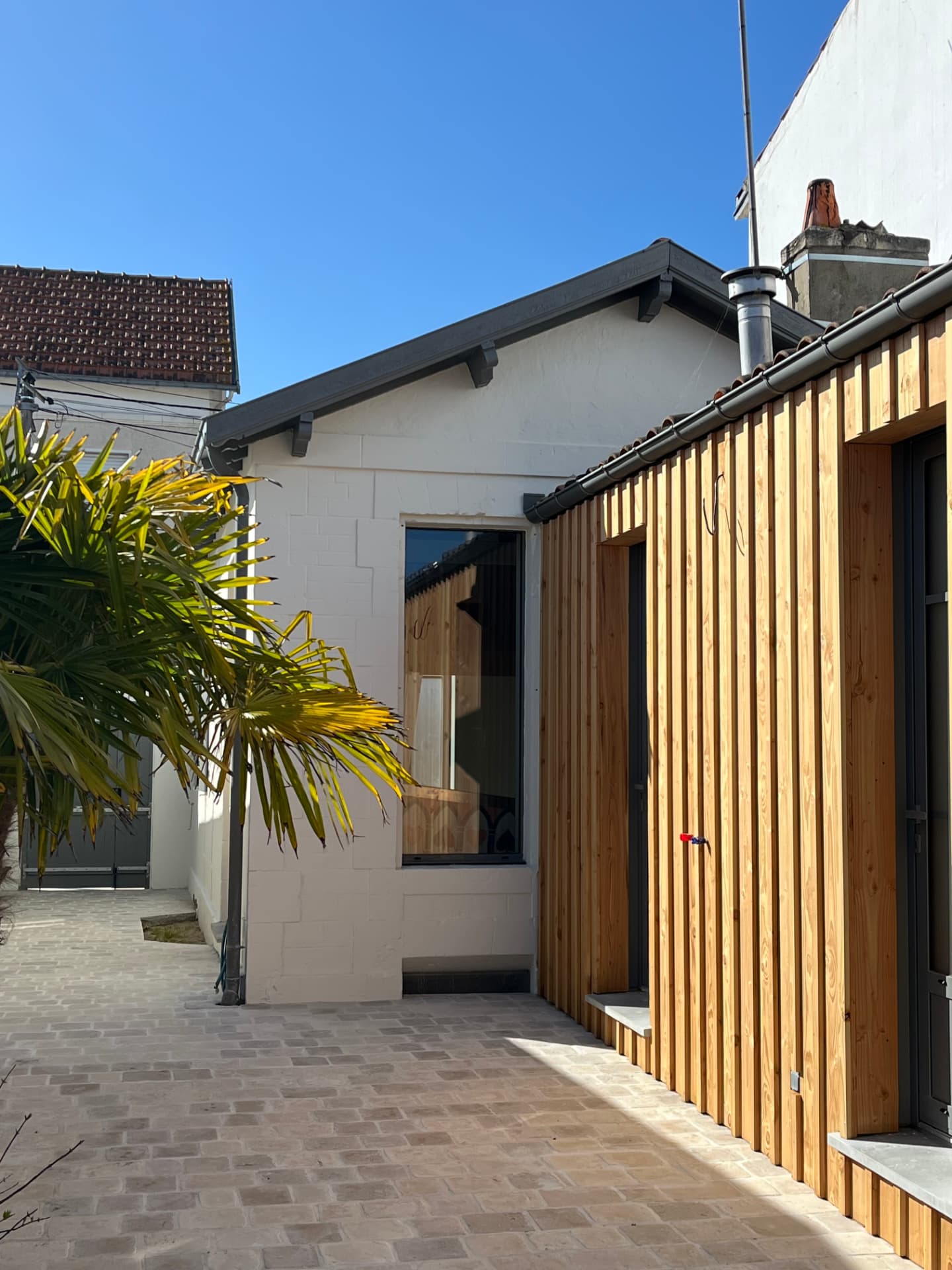 Extension rénovée avec bardage bois et cour pavée
