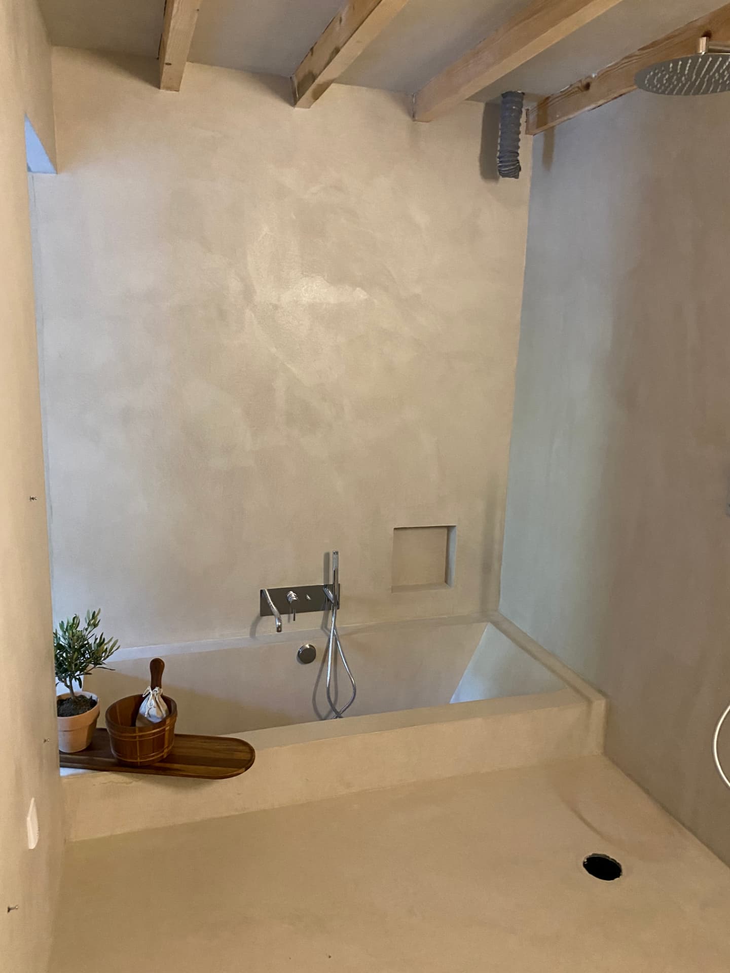 Salle de bain en béton ciré avec baignoire et douche ouverte